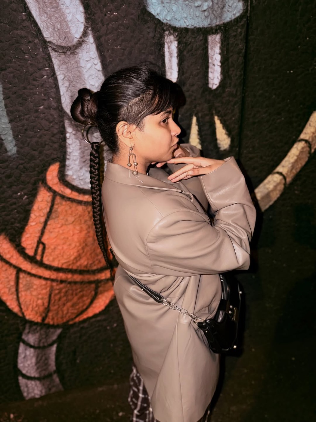 Prerna Singh in a trench coat in front of a mural